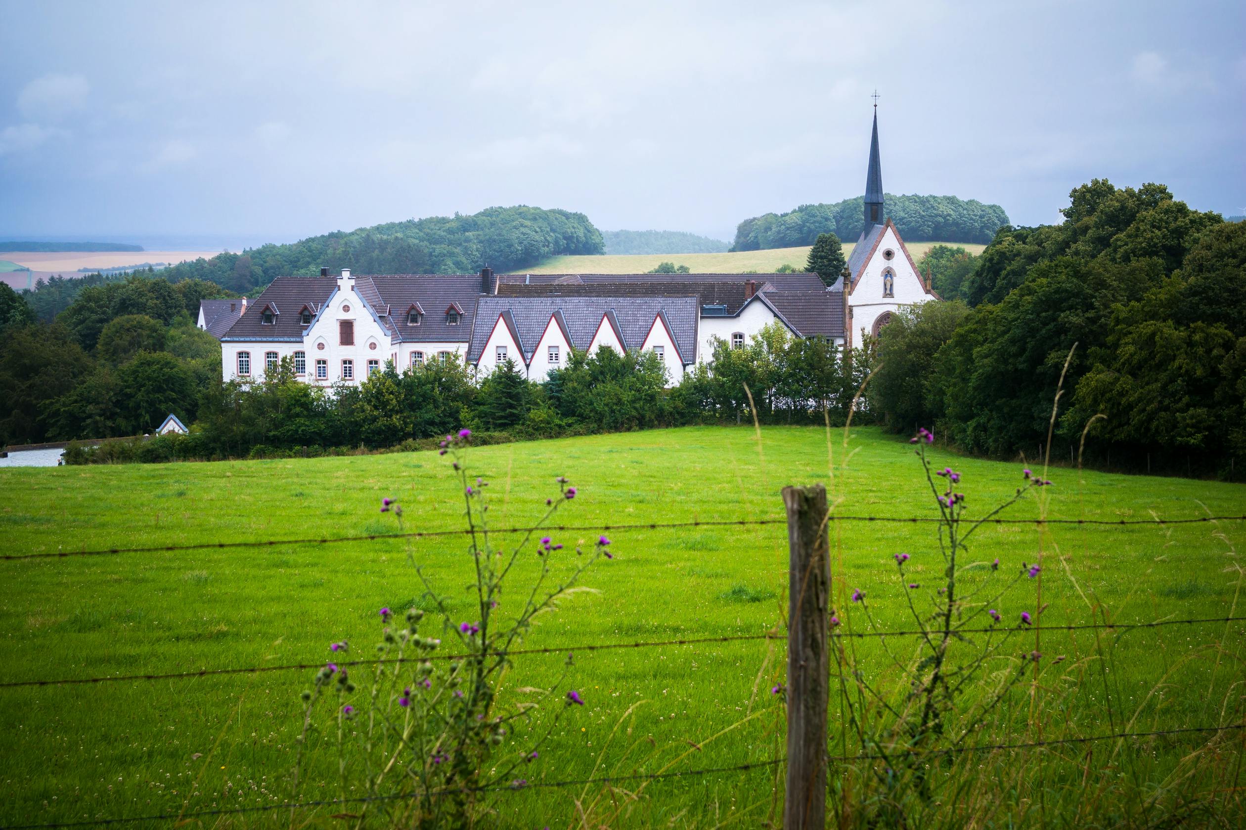 A countryside church with steeple and cross among green fields